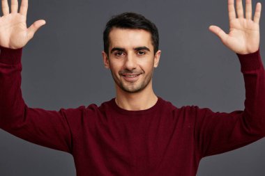 Gülümseyen bir adam el hareketi kırmızı kazak kırpılmış manzara
