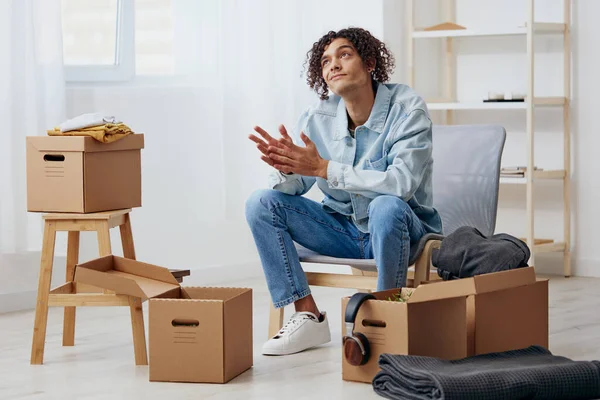 Pohledný chlap sedí na židli s boxy interiér pohybující se interiér — Stock fotografie