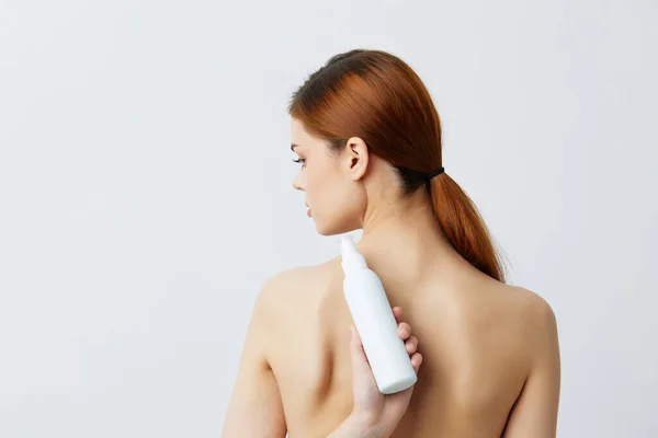 Bella donna lozione per la cura della pelle con spalle nude sfondo grigio — Foto Stock