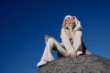 Sonbahar elbiseli turist bir kayanın üzerinde duruyor. Mavi gökyüzü manzarası.