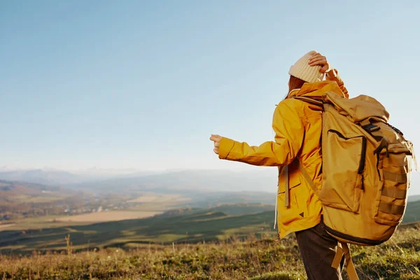Mujer en una chaqueta amarilla en una mochila sombrero viajar montañas Aire fresco — Foto de Stock