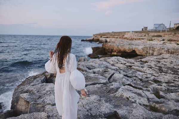 Uzaktaki manzaraya bakan kadın okyanusu değiştirmeden kayalar. — Stok fotoğraf