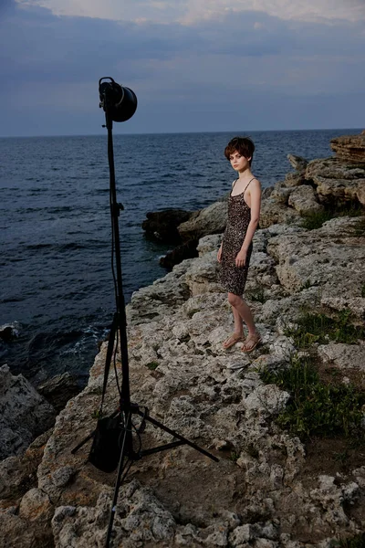 Bela mulher de pé em pedras posando em luxo vestido de praia — Fotografia de Stock