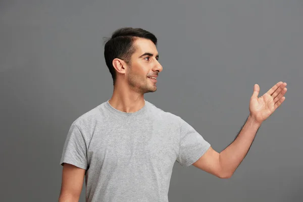 Ritratto uomo divertente grigio t-shirt mano gesto grigio sfondo — Foto Stock