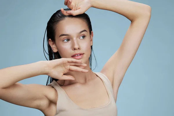 brunette touches the face skin care charm posing studio blue background