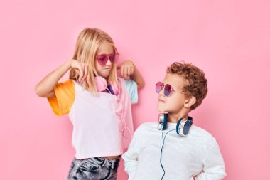 Pembe arka plan oynayan sevimli küçük çocuklar için eğlence kulaklıkları.