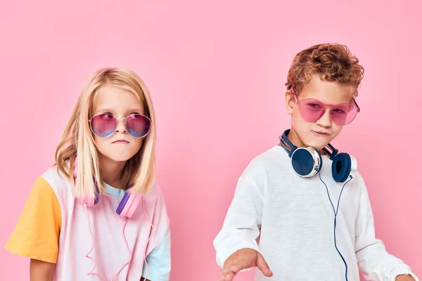 Feliz pareja niño en gafas de sol divertirse con amigos rosa color de fondo —  Fotos de Stock