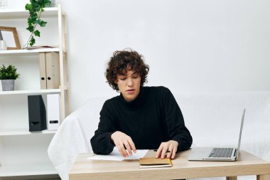 Genç, beyaz bir kanepede dizüstü bilgisayarın önünde iletişim kurmayı öğreniyor. Yüksek kalite fotoğraf