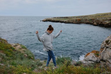 Güzel kadın plaj turizmi bulutlu hava taşlı kıyı rahatlama konsepti. Yüksek kalite fotoğraf
