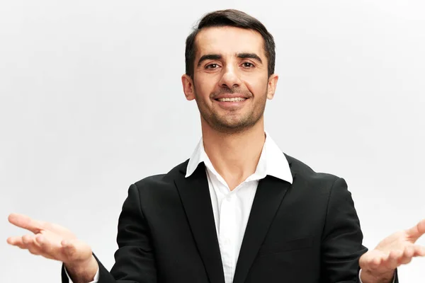 Un uomo in un abito da lavoro nero scrollata di spalle Marketing Manager sguardo di successo sorriso fiducia in se stessi bianco studio sfondo, copiare lo spazio — Foto Stock