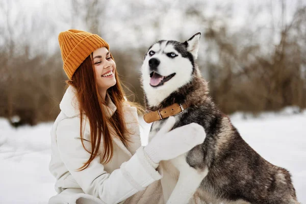 Ung kvinna i snön leker med en hund utomhus vänskap livsstil — Stockfoto