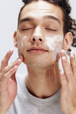 Yüzüne krem süren ve aynaya bakan bir adamın portresi...