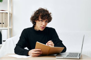 Siyah süveter giyen bir genç masada oturuyor. Yaşam tarzı teknolojisi.