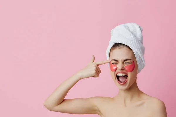 Retrato mulher rosa manchas no rosto com uma toalha na cabeça rosa fundo — Fotografia de Stock