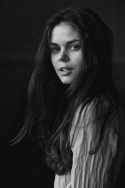 Güzel bir kadın açık havada poz veriyor. Çekici görünüyor. Siyah-beyaz.