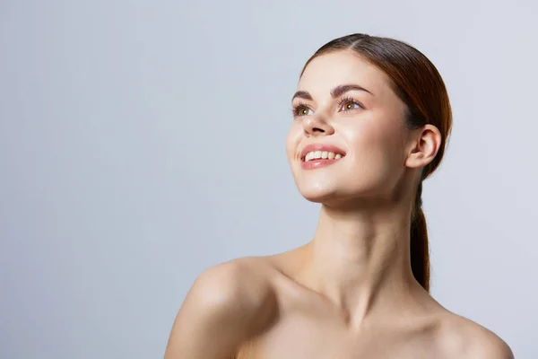 Vrouw glimlachen vrouw blote schouders schoon huid charme licht achtergrond — Stockfoto