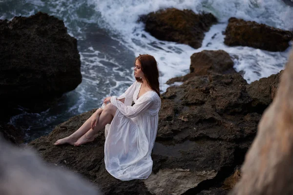Mulher de vestido branco empresa rochosa natureza oceano ondas — Fotografia de Stock
