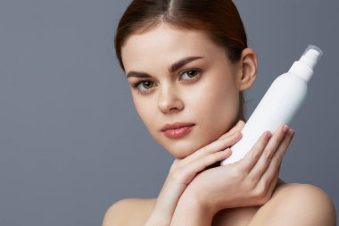 Çıplak omuzlu güzel bir kadın cilt bakım losyonu.