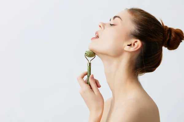 Pretty woman quartz roller scraper skin care massage light background — Stock Photo, Image