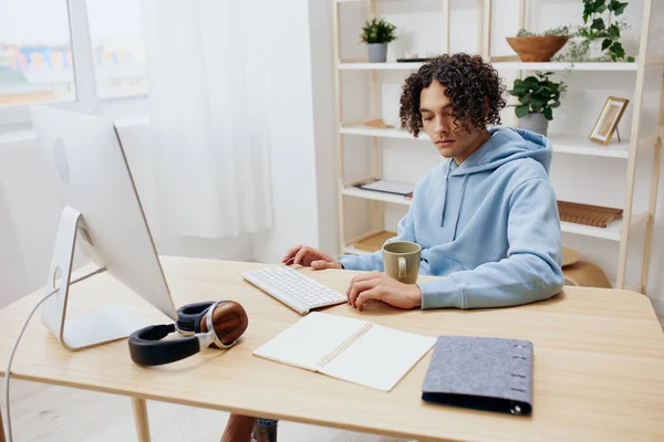 一个留着卷发穿着蓝色夹克的家伙在一个有电话内饰的电脑前 — 图库照片