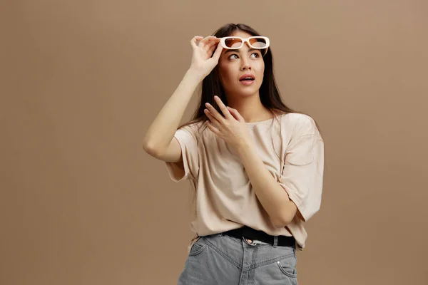 Donna in una t-shirt beige con occhiali posa abbigliamento moda sfondo verde — Foto Stock