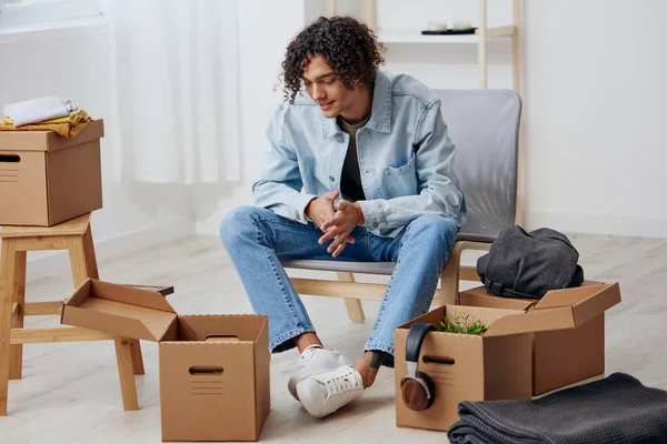 Typ mit lockigem Haar beim Auspacken von Sachen aus Kartons im Zimmer — Stockfoto