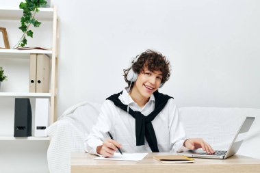 Genç dizüstü bilgisayar kulaklıkla beyaz koltukta yaşam tarzı teknolojisi