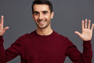 Kırmızı kazaklı bir portre adam el hareketleriyle kendine güvenini belli ediyor.
