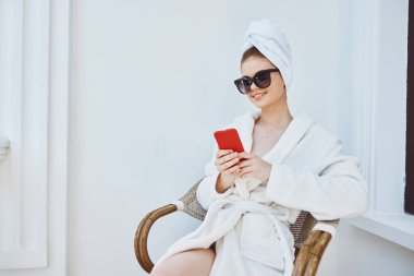 Güneş gözlüklü bir kadın. Sabah dinlenirken telefonu balkonda. Yüksek kalite fotoğraf