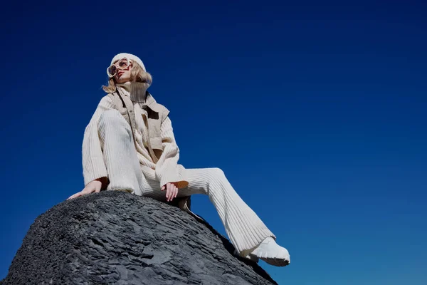 Mujer joven en ropa de otoño se encuentra en un paisaje de roca azul cielo paisaje —  Fotos de Stock