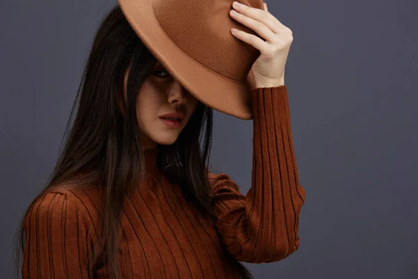 Brunette en chapeau pull marron amusant posant vêtements décontractés fond gris — Photo