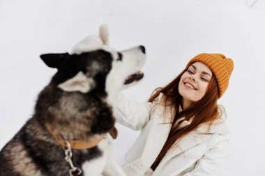 Karda bir kadın köpekle oynuyor. Eğlenceli bir arkadaşlık havası.