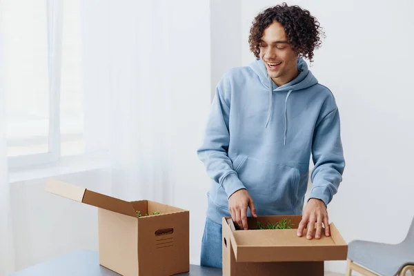Ein junger Mann beim Auspacken von Sachen aus Kartons im Innenraum des Zimmers — Stockfoto