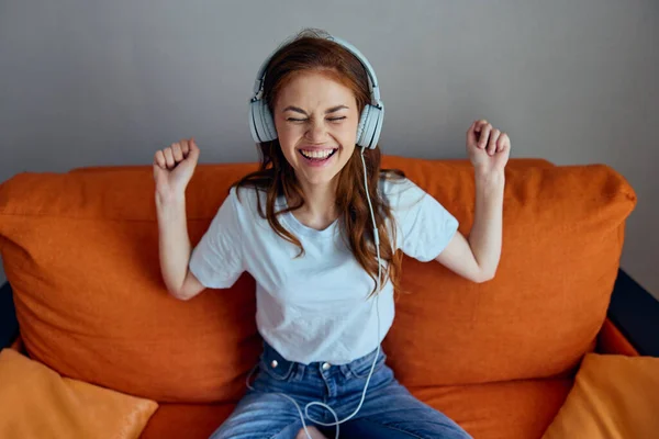 Mulher alegre no sofá laranja ouvir música com fones de ouvido Estilo de vida — Fotografia de Stock