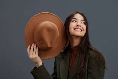 Genç kadın kahverengi şapkalı el, izole edilmiş moda duygularına işaret ediyor.