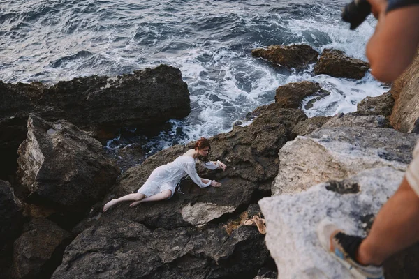 Vista aérea de arriba hacia abajo de la hermosa mujer joven en vestido blanco largo acostado en la costa rocosa con grietas en la superficie rocosa — Foto de Stock