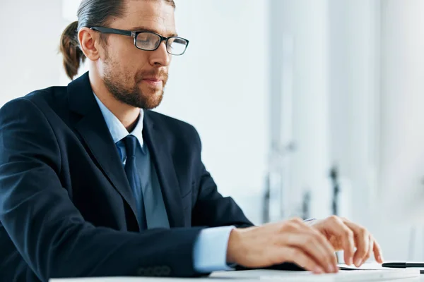 Un homme en costume avec des lunettes tapant à son bureau — Photo