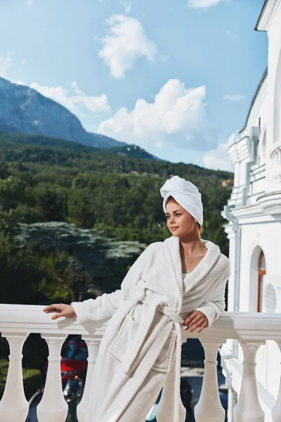 Ritratto donna con un asciugamano in testa in accappatoio bianco soggiorno sul balcone in un hotel concetto di relax — Foto Stock