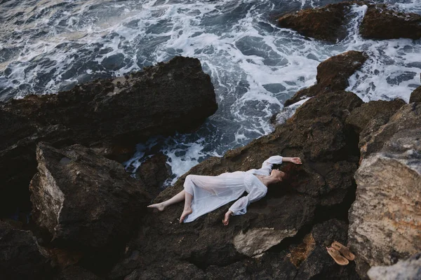 Schöne Braut liegt an felsiger Küste mit Rissen auf felsiger Oberfläche Sommerurlaub Konzept — Stockfoto
