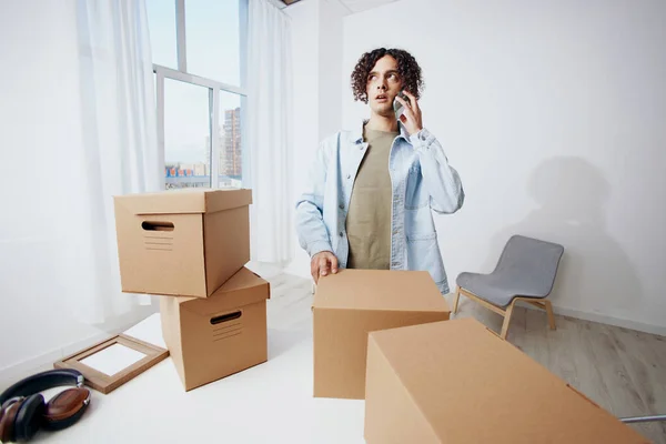 Ein junger Mann beim Auspacken von Sachen aus Kartons im Raum — Stockfoto