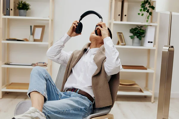 Asiatico uomo maglione su il spalle cuffie musica seduta in il stanza tecnologie — Foto Stock