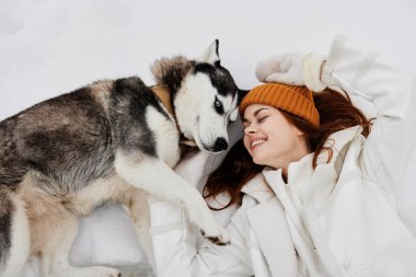 Karda genç bir kadın köpek arkadaşlığıyla oynuyor. Hayat tarzı.