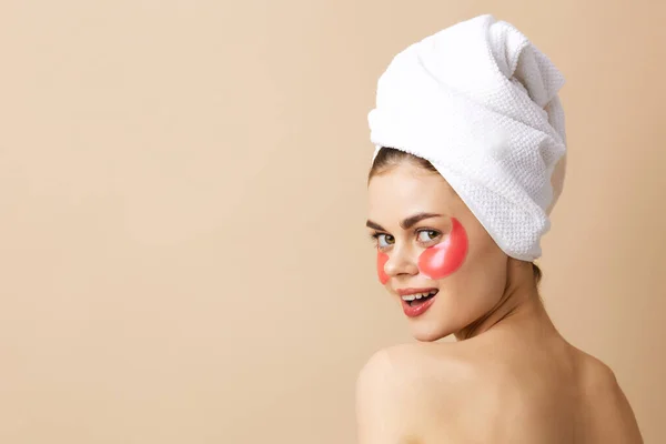 Vacker kvinna med en handduk på huvudet gester med händerna hudvård beige bakgrund — Stockfoto