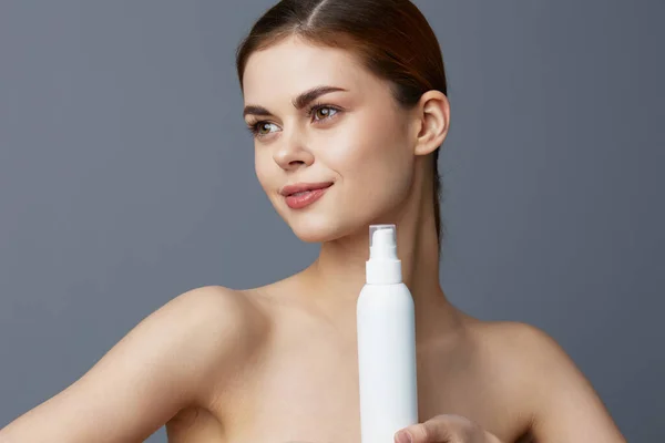 Ritratto donna lozione vaso pelle pulita assistenza sanitaria sfondo grigio — Foto Stock