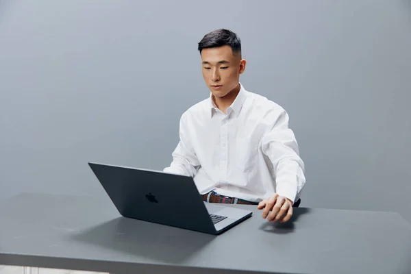 Gerente senta-se em uma mesa na frente de um laptop Internet isolado fundo — Fotografia de Stock