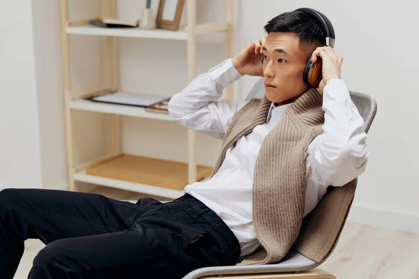 Όμορφος άντρας πουλόβερ στους ώμους ακουστικά μουσική κάθεται στο δωμάτιο Lifestyle — Φωτογραφία Αρχείου