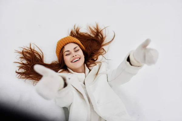 Gelukkige jonge vrouw winterkleding met een hoed ligt op de sneeuw wintervakantie — Stockfoto