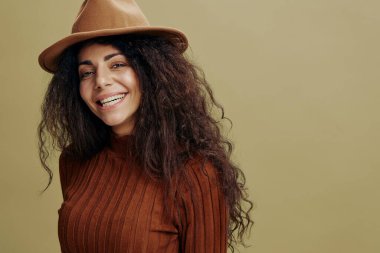 Portreyi kapat. Kahverengi şapkalı aşırı neşeli kıvırcık Latin kadın, kameraya gülümsüyor, gülüyor, evet, izole edilmiş yeşil arka plan diyor. Uzay giysileri moda markalarını kopyalayın, ilanınız için bedava yer. 