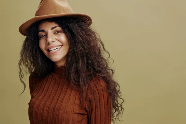 Cierre el retrato. Alegre elegante rizado hembra latina en sombrero marrón, sonriendo a la cámara, riendo, diciendo Sí, fondo verde aislado. Copia espacio ropa marcas de moda, lugar libre para su anuncio. — Foto de Stock