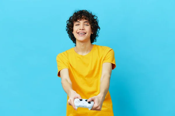 gamer plays with joystick in yellow t-shirts blue background